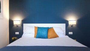 A neatly made bed with white linens and three pillows in blue, orange, and white. - HOLIDAY HOUSE TERRAZZA MANUELA APARTMENTS 1 (Napoli)