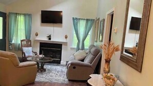 A living room with a fireplace, two sofas, a coffee table, and a TV mounted on the wall. - Become at peace in a comfortable country home (New Paltz)