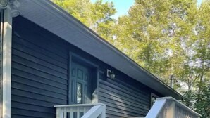 A house with a dark exterior, white exterior stairs, and a small porch area. - Become at peace in a comfortable country home (New Paltz)