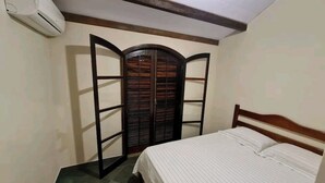 A bedroom with a bed, a wardrobe with a mirror, and an air conditioning unit. - Sítio Borges  (Petrópolis)