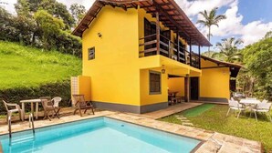 A yellow building with a pool and outdoor seating. - Sítio Borges  (Petrópolis)