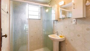 A bathroom with a glass shower enclosure, a sink with a soap dispenser, and a mirror above the sink. - Sítio Borges  (Petrópolis)