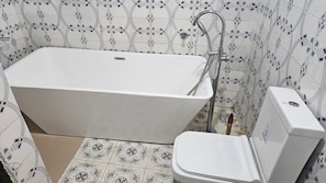Une salle de bain avec une baignoire sur pieds, des toilettes et un bidet.