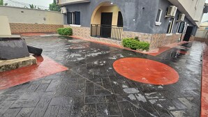A wet outdoor area with tiled flooring, a red circular design, and a building with a balcony. - Enjoy this unique, lavishly furnished 1-bed apartment with "Open Kitchen Design" (Lagos)