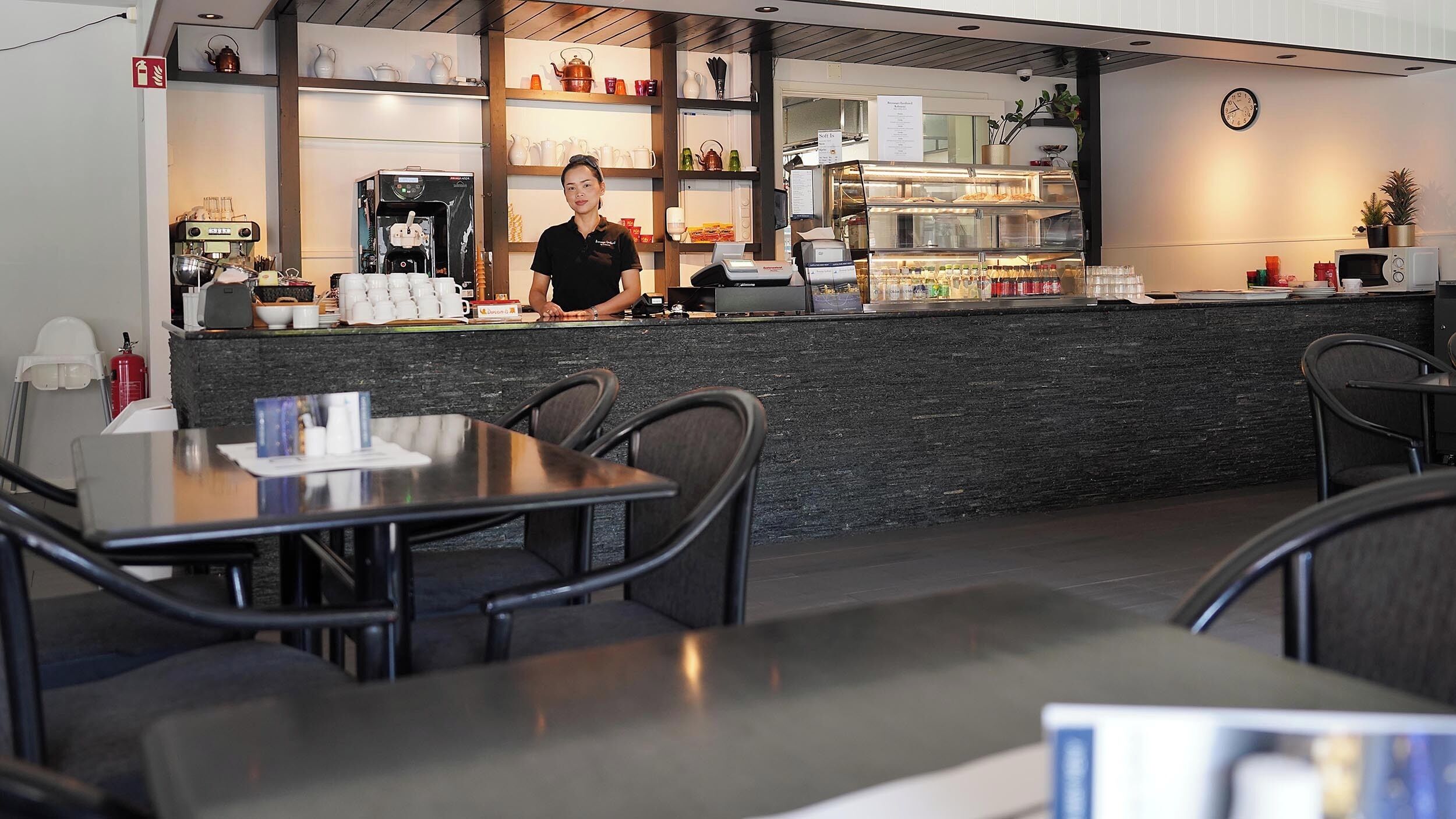 Een café met een balie, koffieapparatuur en een zitgedeelte.