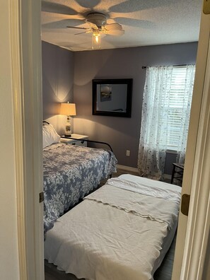 Relax in this serene bedroom with a ceiling fan, bedside lamp, and framed picture on the wall.