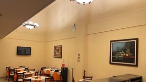 Un salón de conferencias con mesas, sillas, un televisor y obras de arte en las paredes.