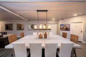 A modern dining area with a long table, white chairs, and decorative vases.