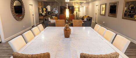 A spacious dining area with a long table, wicker chairs, and a central decorative vase.