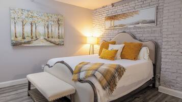 Un dormitorio con cama, banco y dos cuadros en la pared.