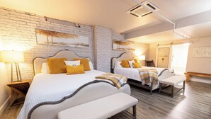 A hotel room with two beds, wooden flooring, and a brick wall. - Boutique hotel in historic downtown Seneca. Room #5, two King beds. (Seneca)