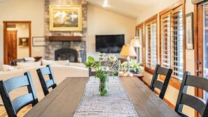 A dining area with a wooden table, black chairs, and a vase of flowers. - Basecamp Stays: Upscale Retreat, Hot Tub, Mtn View (Victor)