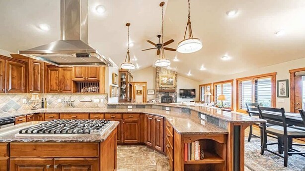 A spacious kitchen with wooden cabinets, a large island, and a stone backsplash. - Basecamp Stays: Upscale Retreat, Hot Tub, Mtn View (Victor)