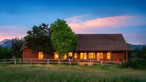 A wooden cabin with a large tree in front, a deck, and a mountain backdrop. - Basecamp Stays: Upscale Retreat, Hot Tub, Mtn View (Victor)