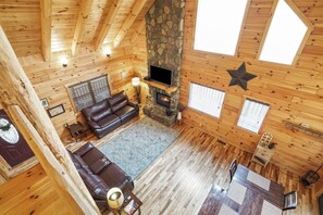 Ein gemütliches Blockhaus mit Kamin aus Stein, Holzwänden, einer Ledersofa und einem Essbereich.