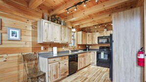 Interno di una baita in legno con angolo cottura dotato di lavastoviglie, microonde e fornello.