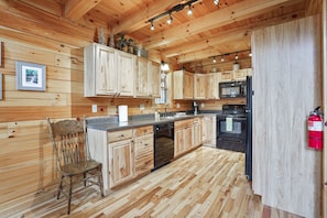 A wooden-paneled kitchen with a dishwasher, stove, and refrigerator.