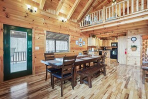 Een houten cabin met een eethoek, keuken en balkon.
