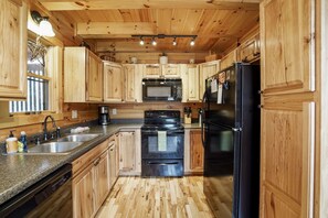 Une cuisine avec des meubles de rangement en bois, un réfrigérateur noir, une cuisinière et un four à micro-ondes.