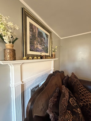 Una habitación con chimenea, un cuadro enmarcado encima y objetos decorativos en la repisa.