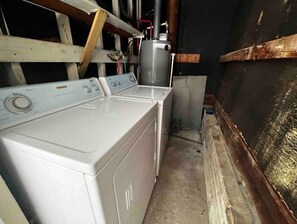 Une buanderie équipée de deux machines à laver et d ’un sèche-linge, avec des poutres en bois au plafond et un sol en béton.