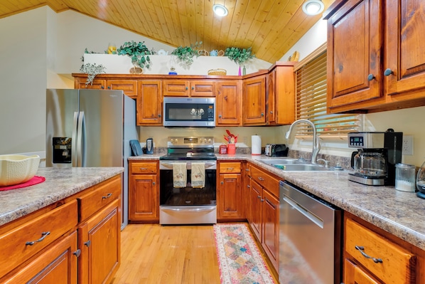 Efficient kitchen with refrigerator, microwave, oven, and dishwasher, perfect for meal preparation.