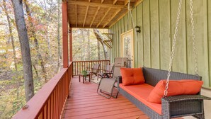 A covered porch with a wicker sofa and chairs, a wooden deck, and a view of trees. - Quiet Murphy Hideaway w/ Decks & Outdoor Fireplace (Murphy)