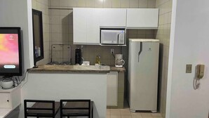 A compact kitchen with a microwave, refrigerator, and a coffee maker on the counter.