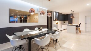 A modern kitchen with a central island, white chairs, and pendant lighting. - Luxurious home in Gradina (Gradina)