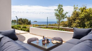 A balcony with a view of the sea, a glass table with drinks, and grey sofas. - Luxurious home in Gradina (Gradina)