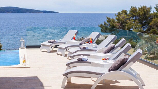 A row of white sun loungers with towels and drinks, overlooking a pool and the sea. - Luxurious home in Gradina (Gradina)