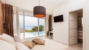 A bedroom with a large bed, a TV, a desk, and a view of the sea. - Luxurious home in Gradina (Gradina)
