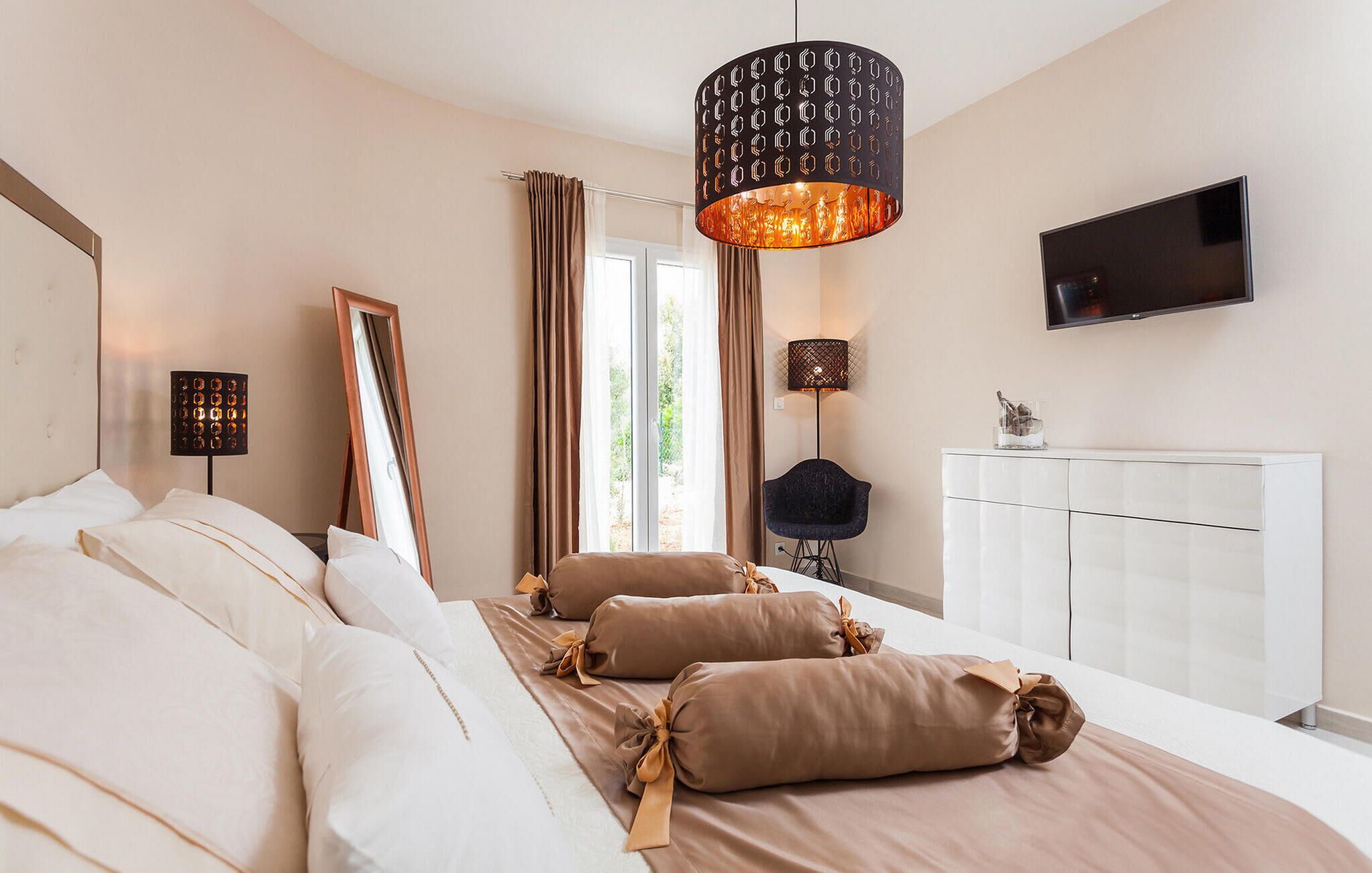 A modern bedroom with a large bed, a television, and a window with curtains.