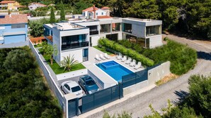 Una casa moderna de dos pisos con piscina, garaje y entrada para vehículos.