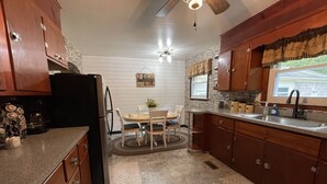 A kitchen with wooden cabinets, a refrigerator, a dining table with chairs, and a window with a view. - Beautiful Mountain View’s and Located on several acres for privacy (Chapmanville)