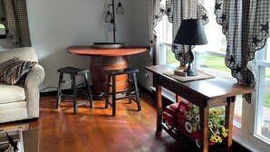 A cozy room with a wooden barrel table, two bar stools, a lamp, and a small table with a flower arrangement. - Beautiful Mountain View’s and Located on several acres for privacy (Chapmanville)