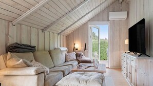 A cozy, wooden-paneled room with a sofa, a television, and a window offering a view of greenery. - Awesome home in Hejls with WiFi (Hejls)