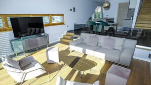 Una sala de estar moderna con un sofá, sillones, una mesa de centro y un televisor.