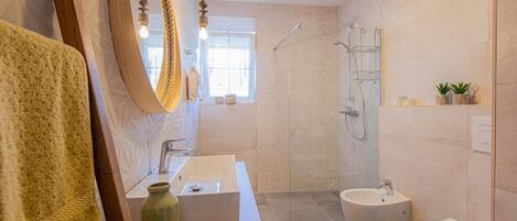 A modern bathroom with a wooden vanity, a large mirror, a shower, and a toilet.
