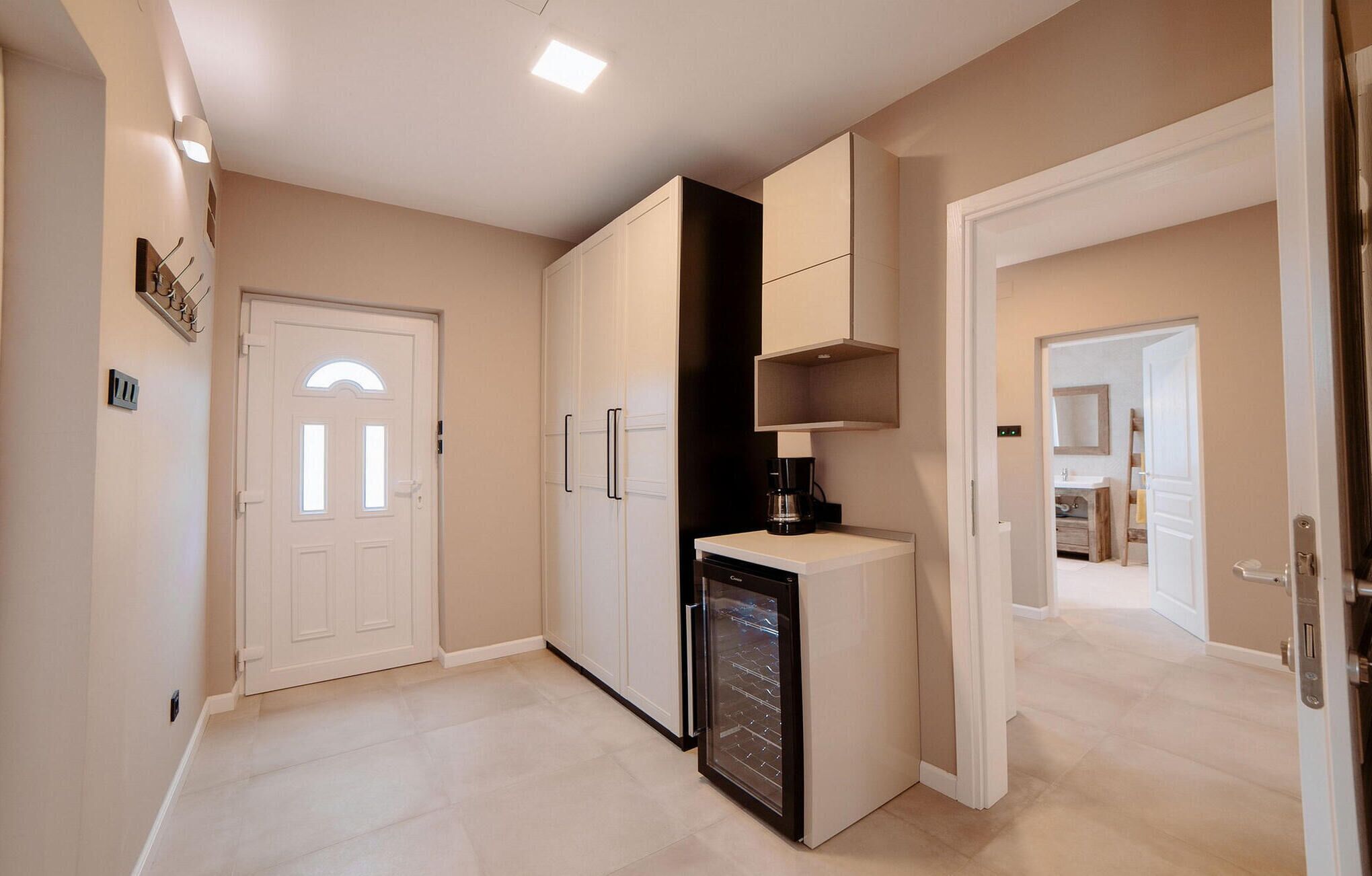 A modern kitchen with white cabinetry, a built-in dishwasher, and a coffee machine.