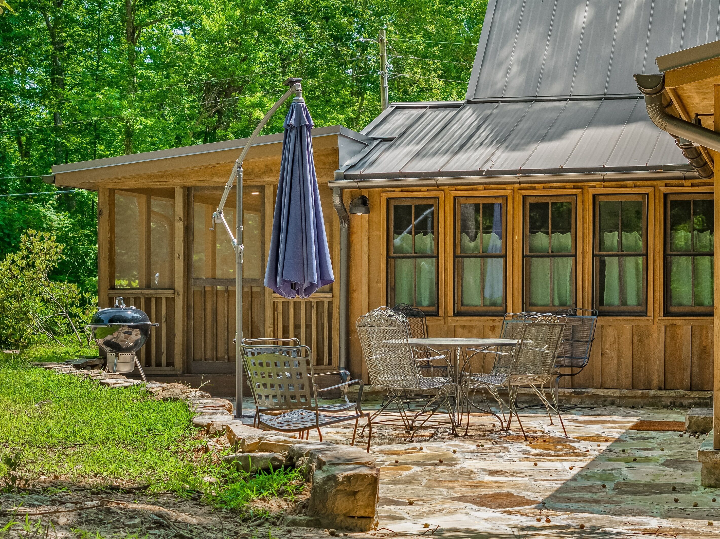Une cabane en bois dotée d’un patio aménagé avec du mobilier d’extérieur et un barbecue.