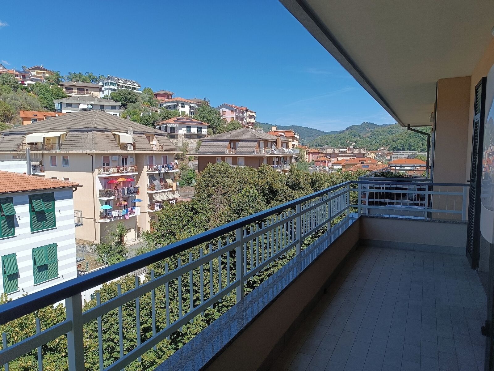 A balcony with a view of a residential area, including houses and greenery.