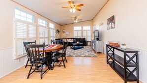 A spacious living area with a dining table, chairs, a sofa, and a ceiling fan. - Set up for Crews- 10 beds, 5 bedrooms, 3 full bath (Byron)