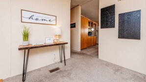 A hallway with a wooden console table, a wall-mounted sign reading "home," and two wall art pieces. - Set up for Crews- 10 beds, 5 bedrooms, 3 full bath (Byron)