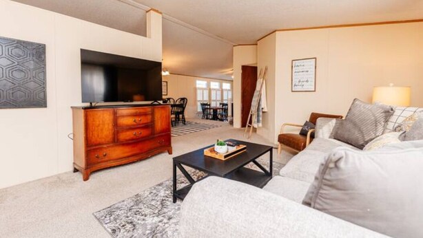 A living room with a sofa, coffee table, TV, and a wooden cabinet. - Set up for Crews- 10 beds, 5 bedrooms, 3 full bath (Byron)
