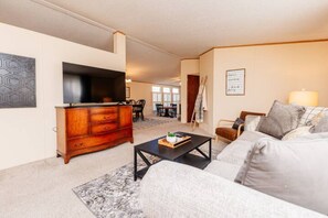 A living room with a sofa, coffee table, TV, and a wooden cabinet.