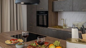 Een moderne keuken met donkere kastjes, een ingebouwde oven en een RVS-spoelbak.