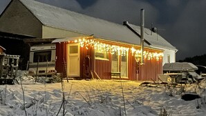 A snow-covered landscape with a wooden cabin featuring a porch decorated with lights. - Tiny House Anneliese, Air Conditioning, E-Bikes, Dogs Welcome (Oberbettingen)