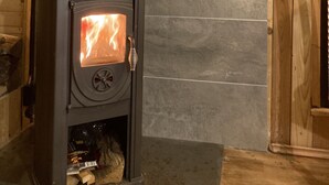 A wood-burning stove with a visible fire, set against a tiled wall with a geometric pattern. - Tiny House Anneliese, Air Conditioning, E-Bikes, Dogs Welcome (Oberbettingen)