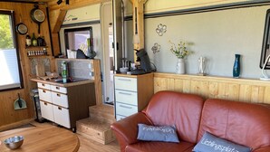 A compact RV interior with a kitchenette, a dining area, and a seating area with a leather couch and pillows. - Tiny House Anneliese, Air Conditioning, E-Bikes, Dogs Welcome (Oberbettingen)